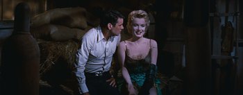Movie still from “Bus Stop” (1956), directed by Joshua Logan – A man standing next to a woman in a green dress; Medium shot, Over the shoulder angle