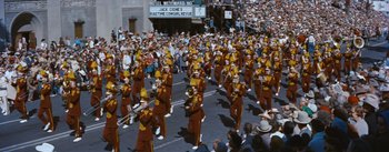 Movie still from “Bus Stop” (1956), directed by Joshua Logan – A parade with a large crowd of people and a marching band; Extreme Wide shot, High angle