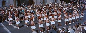 Movie still from “Bus Stop” (1956), directed by Joshua Logan – A crowd of people are gathered together in a parade; Wide shot, High angle