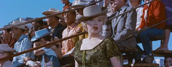 Movie still from “Bus Stop” (1956), directed by Joshua Logan – A woman wearing a cowboy hat in front of a group of people; Medium shot, Low angle