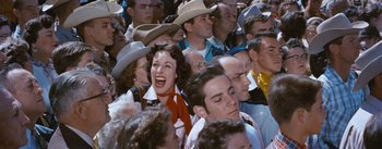 Movie still from “Bus Stop” (1956), directed by Joshua Logan – A group of people that are sitting in a crowd; Medium shot, High angle