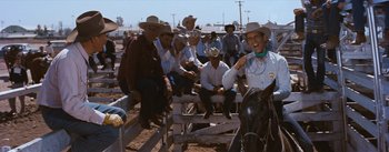 Movie still from “Bus Stop” (1956), directed by Joshua Logan – A group of men sitting on top of a wooden bench; Medium shot, Over the shoulder angle