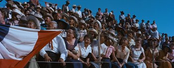Movie still from “Bus Stop” (1956), directed by Joshua Logan – A group of people sitting in the bleachers at an event; Extreme Wide shot, High angle