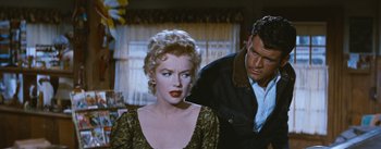 Movie still from “Bus Stop” (1956), directed by Joshua Logan – A man and a woman are standing next to each other in a room; Medium shot, Over the shoulder angle