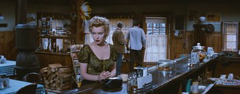 Movie still from “Bus Stop” (1956), directed by Joshua Logan – A woman sitting at a counter in front of two men; Medium shot, Over the shoulder angle