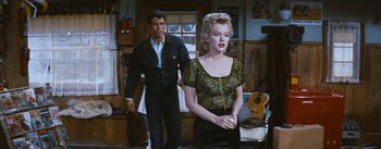 Movie still from “Bus Stop” (1956), directed by Joshua Logan – A man and a woman standing next to each other in a room; Medium shot, Over the shoulder angle