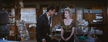 Movie still from “Bus Stop” (1956), directed by Joshua Logan – A man and a woman sitting on a wooden floor; Medium shot, Over the shoulder angle