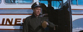 Movie still from “Bus Stop” (1956), directed by Joshua Logan – A man wearing a hat and gloves standing in front of a bus; Medium shot, Low angle