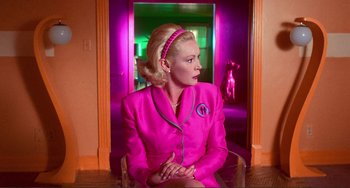 A woman in a pink suit sitting in front of a doorway