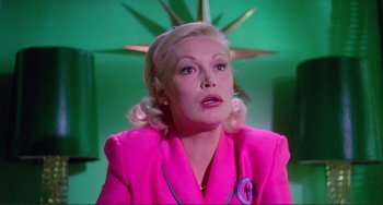 An older woman in a pink jacket looking up