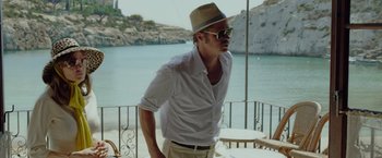 Movie still from “By the Sea” (2015), directed by Angelina Jolie – A man wearing a hat and sunglasses standing on a balcony; Medium shot, Low angle