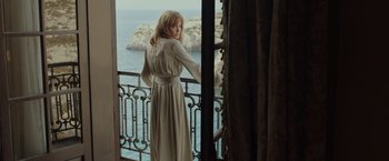 A woman standing on a balcony looking out at the ocean