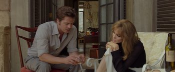 Movie still from “By the Sea” (2015), directed by Angelina Jolie – A man and a woman sitting at a table with a glass of wine; Medium shot, Over the shoulder angle