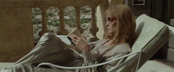 Movie still from “By the Sea” (2015), directed by Angelina Jolie – A woman sitting in a chair while reading a book; Medium shot, High angle