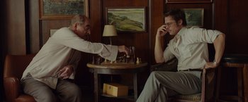 Movie still from “By the Sea” (2015), directed by Angelina Jolie – Two men are playing a game of chess on their cell phones; Medium shot, Over the shoulder angle
