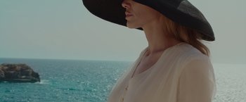 Movie still from “By the Sea” (2015), directed by Angelina Jolie – A woman wearing a black hat standing in front of the ocean; Close Up shot, Low angle
