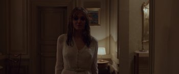 A woman in a white dress standing in front of a lamp