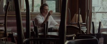 Movie still from “By the Sea” (2015), directed by Angelina Jolie – A man sitting at a table in front of a plate of food; Medium shot, High angle