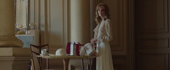 Movie still from “By the Sea” (2015), directed by Angelina Jolie – A woman in a white dress standing next to a table; Medium shot, Low angle