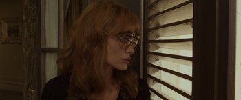 A woman wearing glasses looking out of a window