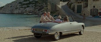 Movie still from “By the Sea” (2015), directed by Angelina Jolie – A group of people sitting in the back of an old car; Wide shot, High angle