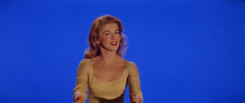 Movie still from “Bye Bye Birdie” (1963), directed by George Sidney – A woman in a tan top is holding her hands out; Medium shot, Low angle