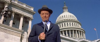 Movie still from “Bye Bye Birdie” (1963), directed by George Sidney – A man in a suit and hat holding a microphone; Medium shot, Low angle