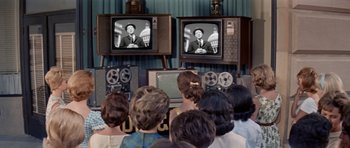 Movie still from “Bye Bye Birdie” (1963), directed by George Sidney – A group of people sitting in front of two televisons; Medium shot, High angle
