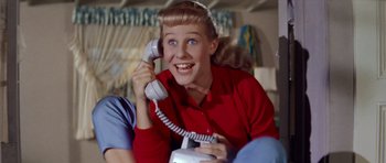 Movie still from “Bye Bye Birdie” (1963), directed by George Sidney – A young woman sitting on a couch talking on a phone; Close Up shot, Low angle