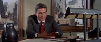 Movie still from “Bye Bye Birdie” (1963), directed by George Sidney – A man in a business suit sitting at a desk; Medium shot, Low angle