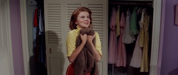 Movie still from “Bye Bye Birdie” (1963), directed by George Sidney – A young woman holding a brown teddy bear in front of a closet; Medium shot, Low angle