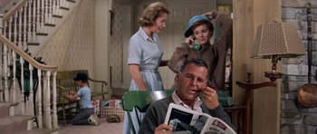 Movie still from “Bye Bye Birdie” (1963), directed by George Sidney – A man sitting in front of two women while talking on a phone; Medium shot, Low angle