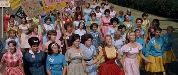 Movie still from “Bye Bye Birdie” (1963), directed by George Sidney – A large group of women in dresses holding signs; Medium shot, High angle