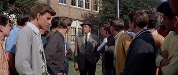 Movie still from “Bye Bye Birdie” (1963), directed by George Sidney – A group of men standing around a building; Medium shot, Over the shoulder angle