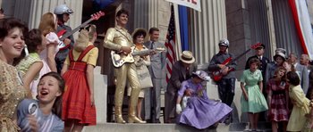 Movie still from “Bye Bye Birdie” (1963), directed by George Sidney – A group of people standing on steps in front of a building; Wide shot, Low angle