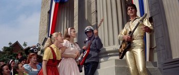 Movie still from “Bye Bye Birdie” (1963), directed by George Sidney – A group of people standing next to each other holding guitars; Medium shot, Low angle