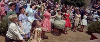 Movie still from “Bye Bye Birdie” (1963), directed by George Sidney – A group of people dancing on a dirt field; Medium shot, High angle