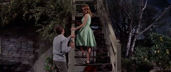 Movie still from “Bye Bye Birdie” (1963), directed by George Sidney – A woman in a green dress standing next to a man; Wide shot, Low angle