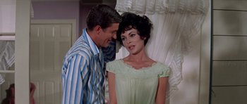 Movie still from “Bye Bye Birdie” (1963), directed by George Sidney – A man standing next to a woman wearing a dress; Medium shot, Over the shoulder angle