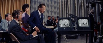 Movie still from “Bye Bye Birdie” (1963), directed by George Sidney – A man sitting in front of an old television; Wide shot, Over the shoulder angle