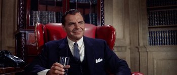 Movie still from “Bye Bye Birdie” (1963), directed by George Sidney – An older man sitting in a chair holding a glass of wine; Medium shot, Over the shoulder angle