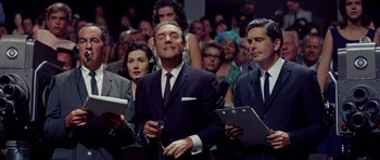 Movie still from “Bye Bye Birdie” (1963), directed by George Sidney – A group of men in suits and ties holding clipboards; Medium shot, Low angle