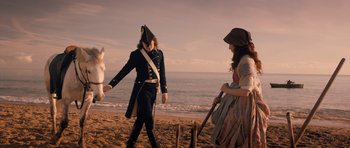 Movie still from “Byzantium” (2012), directed by Neil Jordan – A man and a woman dressed in period clothing walk on the beach; Wide shot, Over the shoulder angle