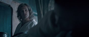 Movie still from “Byzantium” (2012), directed by Neil Jordan – A woman sitting on a bed next to a curtain; Medium shot, Over the shoulder angle