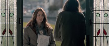 Movie still from “Byzantium” (2012), directed by Neil Jordan – A woman holding a piece of paper while standing next to another woman; Medium shot, Over the shoulder angle
