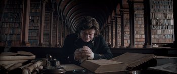 Movie still from “Byzantium” (2012), directed by Neil Jordan – A person sitting at a table with a box in front of him; Medium shot, Low angle