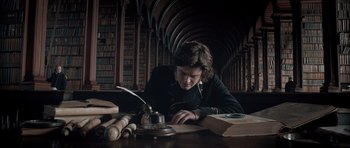 Movie still from “Byzantium” (2012), directed by Neil Jordan – A person sitting at a table writing on a paper; Medium shot, Low angle