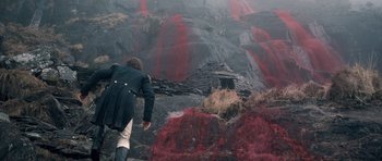 Movie still from “Byzantium” (2012), directed by Neil Jordan – A man in a blue coat is looking down at a mountain of red lava; Wide shot, High angle