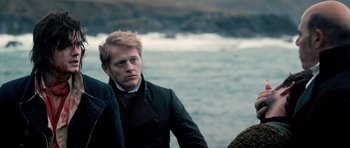 Movie still from “Byzantium” (2012), directed by Neil Jordan – A man in a black jacket standing next to a body of water; Close Up shot, Over the shoulder angle