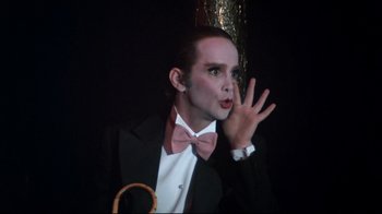 Movie still from “Cabaret” (1972), directed by Bob Fosse – A man in a suit and bow tie holding his hand up to his face; Close Up shot, Low angle